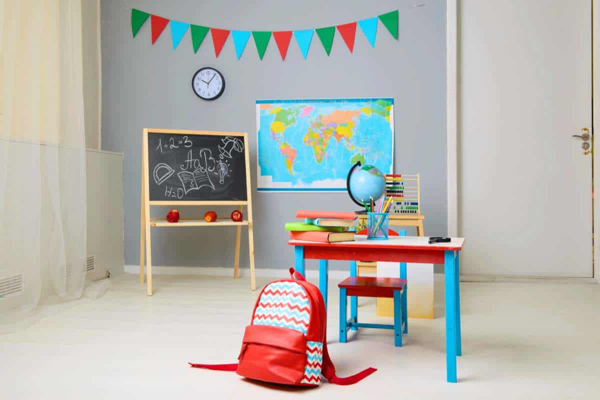 Multi-functional homeschool room in a laundry area, showcasing a chalkboard, world map, and a small study table with a red backpack, highlighting practical homeschool room ideas.