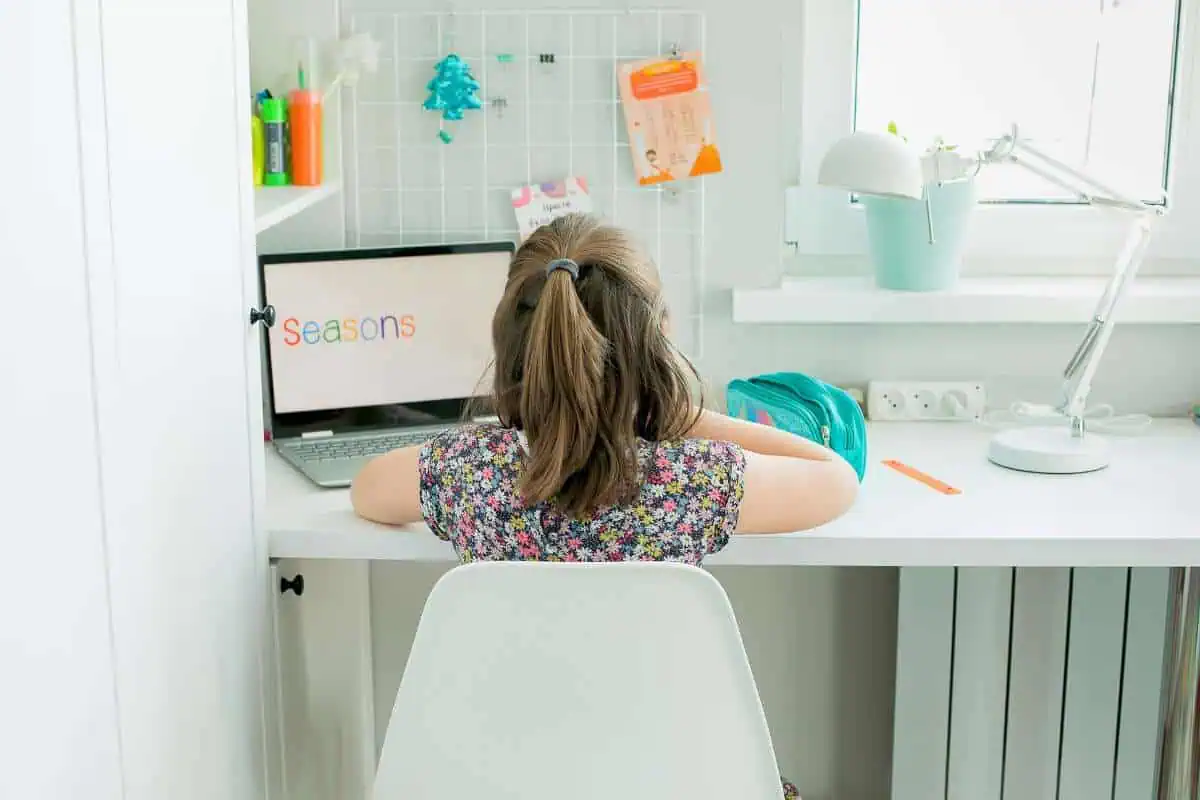 Homeschool office setup with a small desk, colorful art supplies, and a laptop displaying 'Seasons,' perfect for homeschool room ideas.