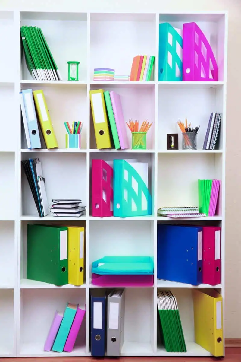 Organized bookshelf with colorful binders, notebooks, and pencils, illustrating effective homeschooling tips for maintaining an orderly study space.