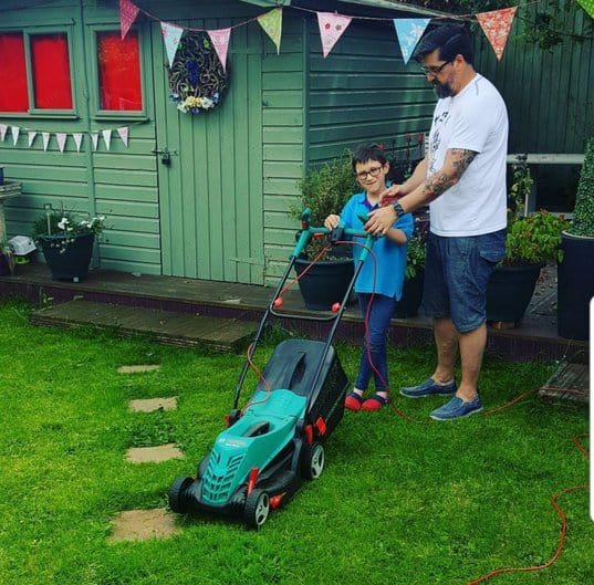 dad and young son gardening with a lawnmower.