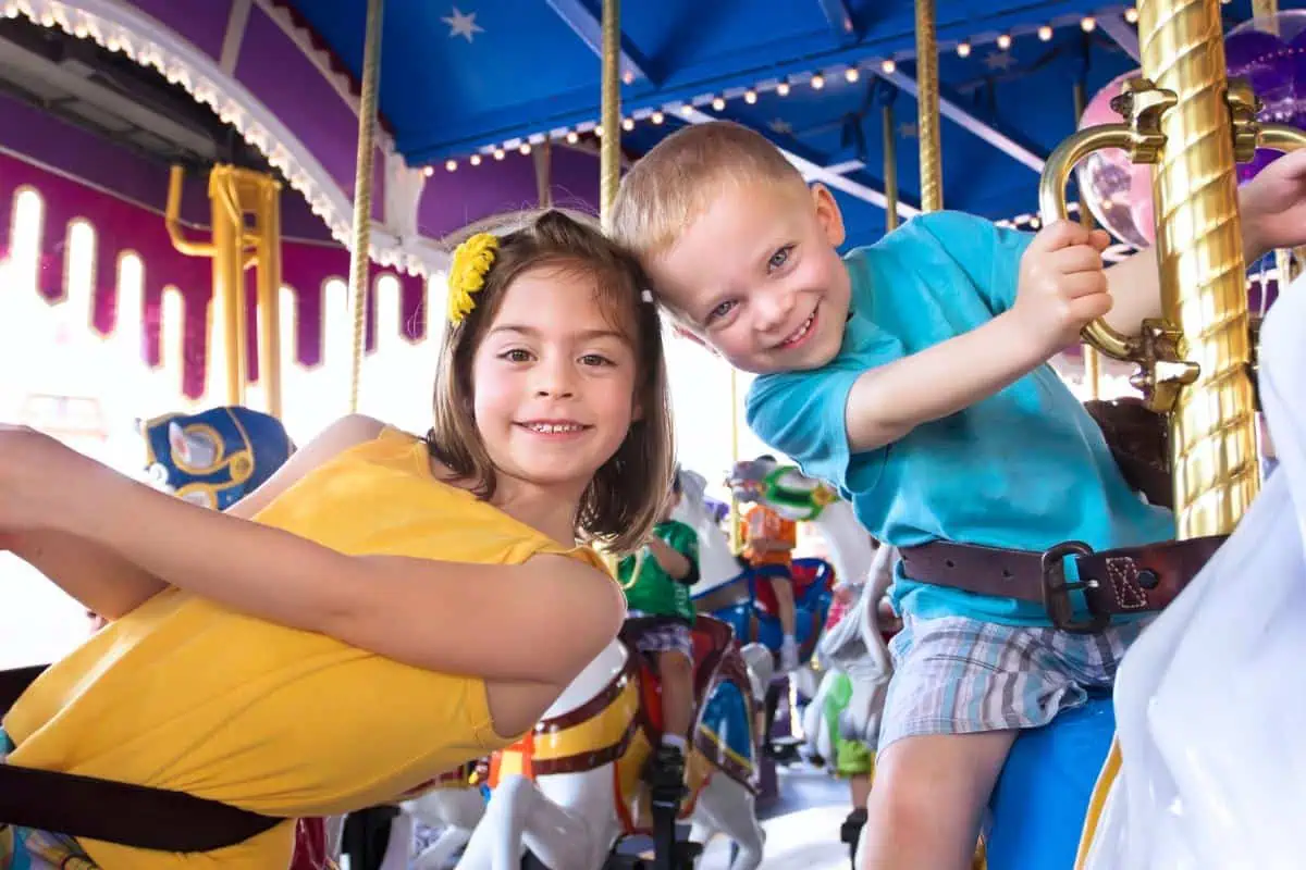 a boy and a girl riding a carousel having fun in the summer