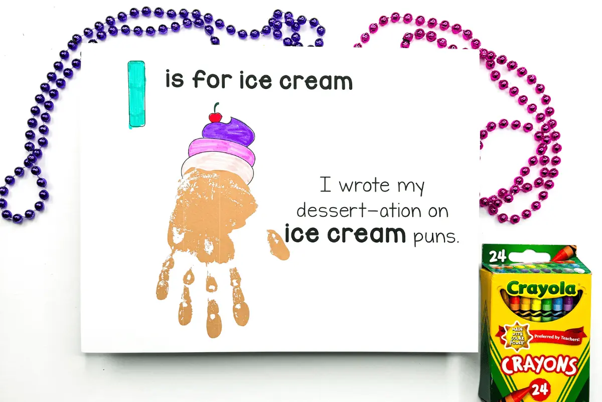 Handprint artwork for a child's educational activity, depicting an ice cream cone using a handprint as the cone and painted scoops of ice cream on top. The words 'I is for ice cream' and a clever pun are included, showcasing a creative way to learn the alphabet and enjoy craft time. Mardi Gras beads and Crayola crayons are placed around the artwork, emphasizing the fun and hands-on learning experience.