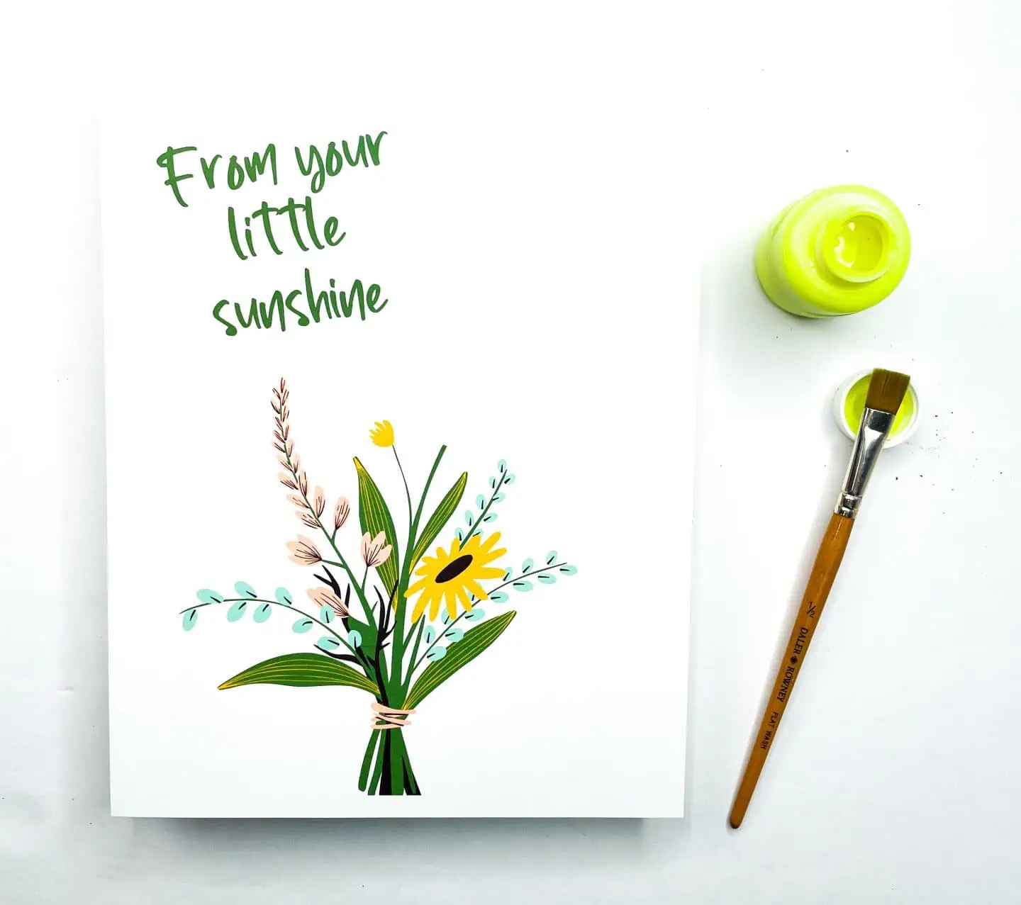 A handprint art printable reading "From your little sunshine" with a bouquet of illustrated flowers, beside a paintbrush and open pot of yellow paint.

