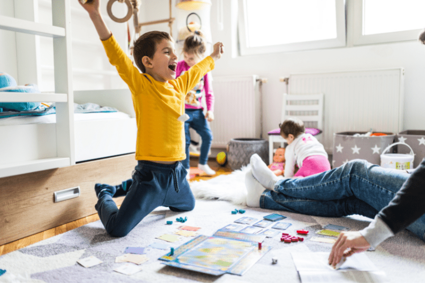 Young 7 year old boy jumping for joy after winning his favorite board game.