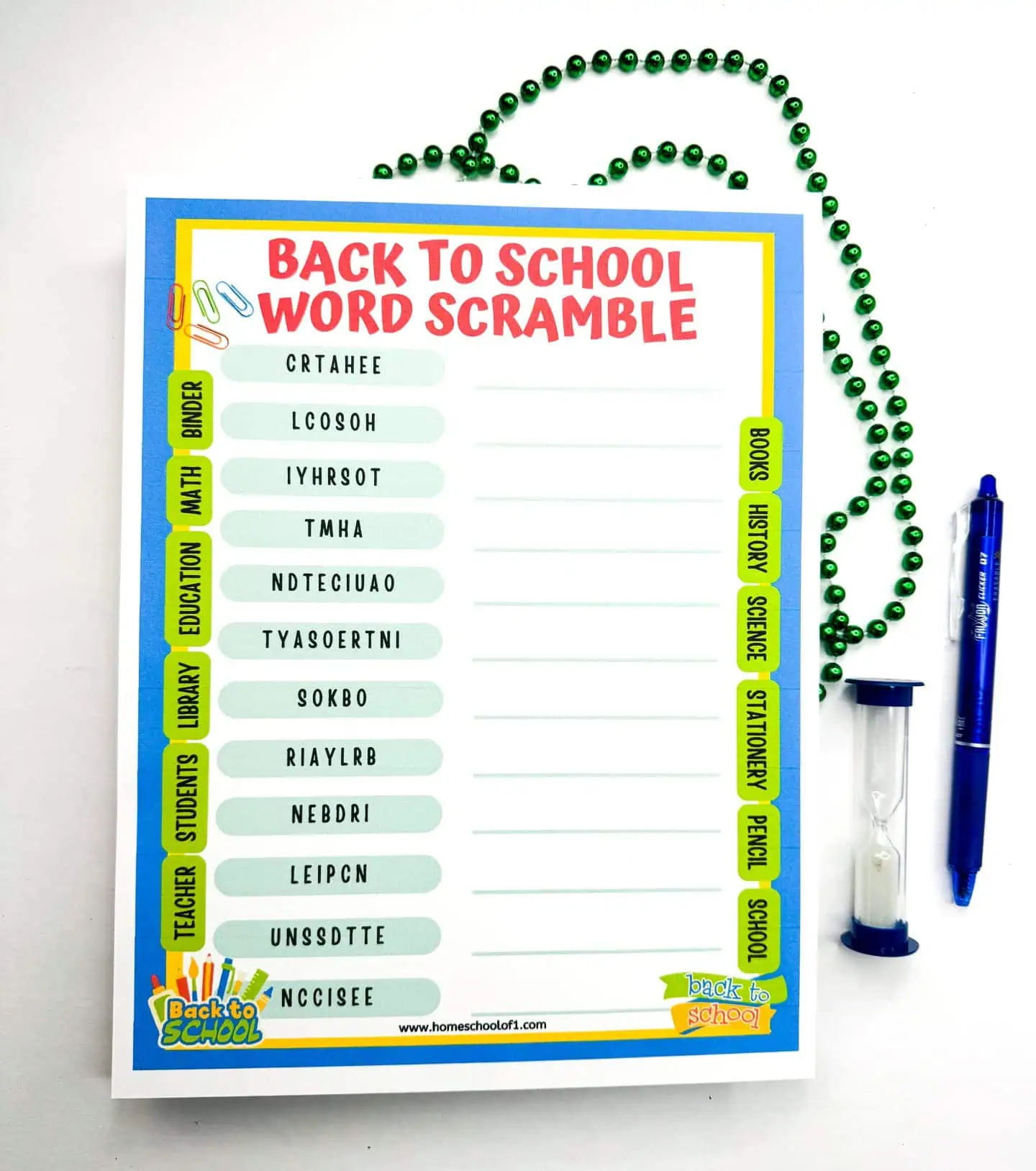 A single 'Back to School Word Scramble' sheet with green bead decorations forming a heart shape above it and a blue pen lying to the right. Educational scramble words like 'HISTORY' and 'PENCIL' await solving, with a blue and yellow border framing the page.