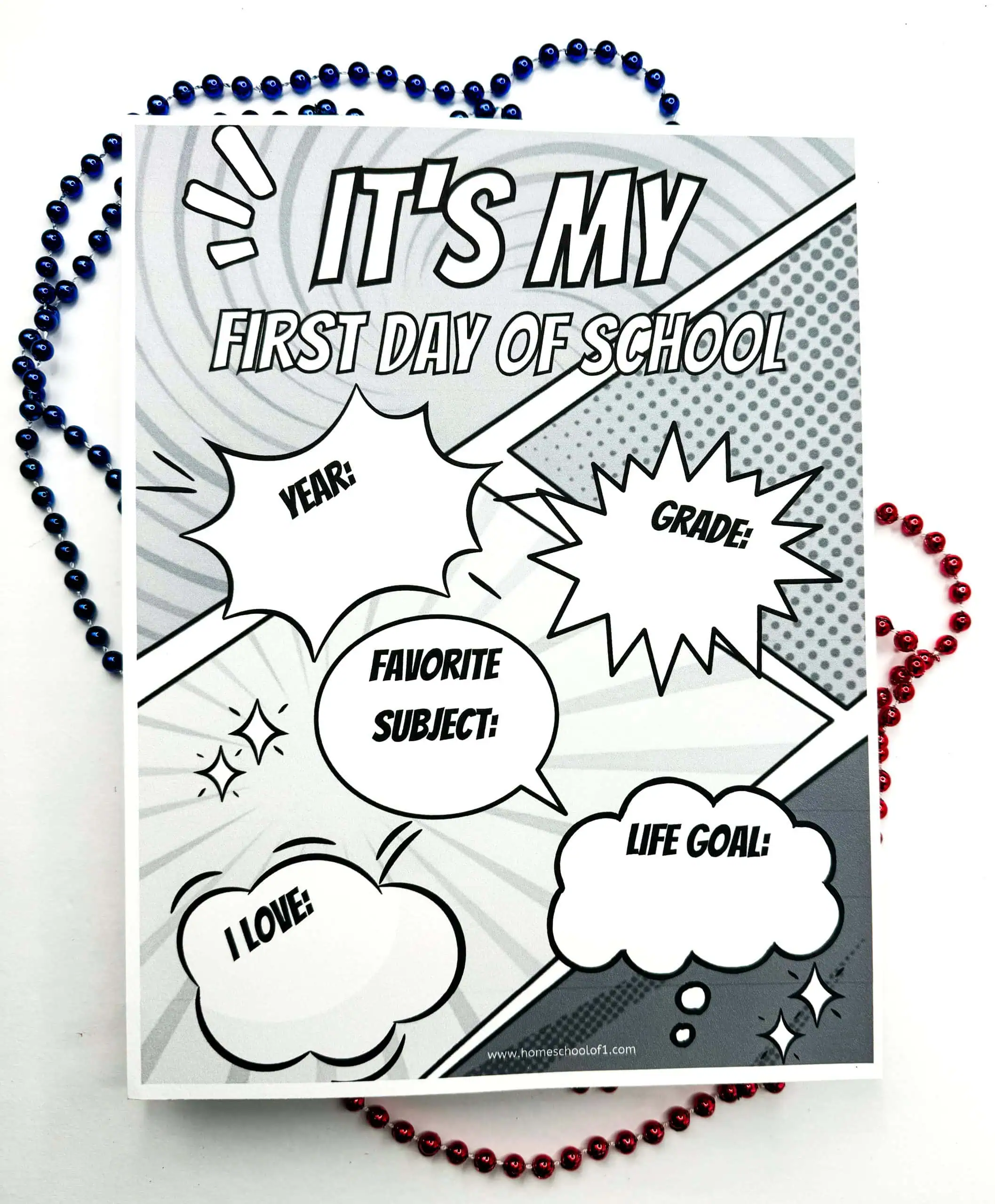 Black and white 'First Day of School' sign with a pop art theme and comic-style bursts surrounding customizable text fields for 'YEAR,' 'GRADE,' 'FAVORITE SUBJECT,' 'LIFE GOAL,' and 'I LOVE.' Encircled by a blue beaded necklace