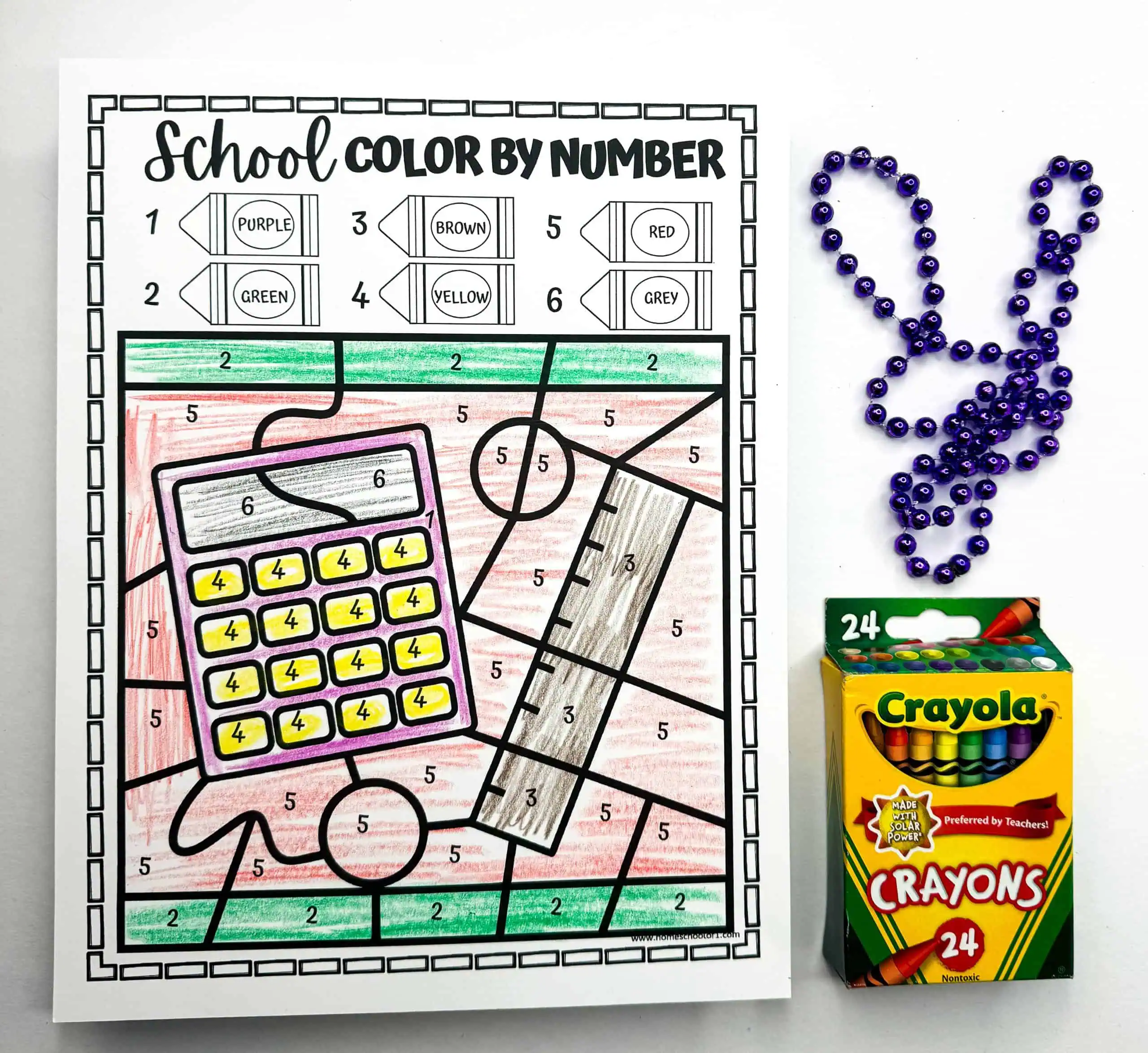 A color by number worksheet featuring a calculator with each button and section colored according to the number guide at the top. Beads form the shape of a rabbit, and a box of Crayola crayons indicates a coloring activity.