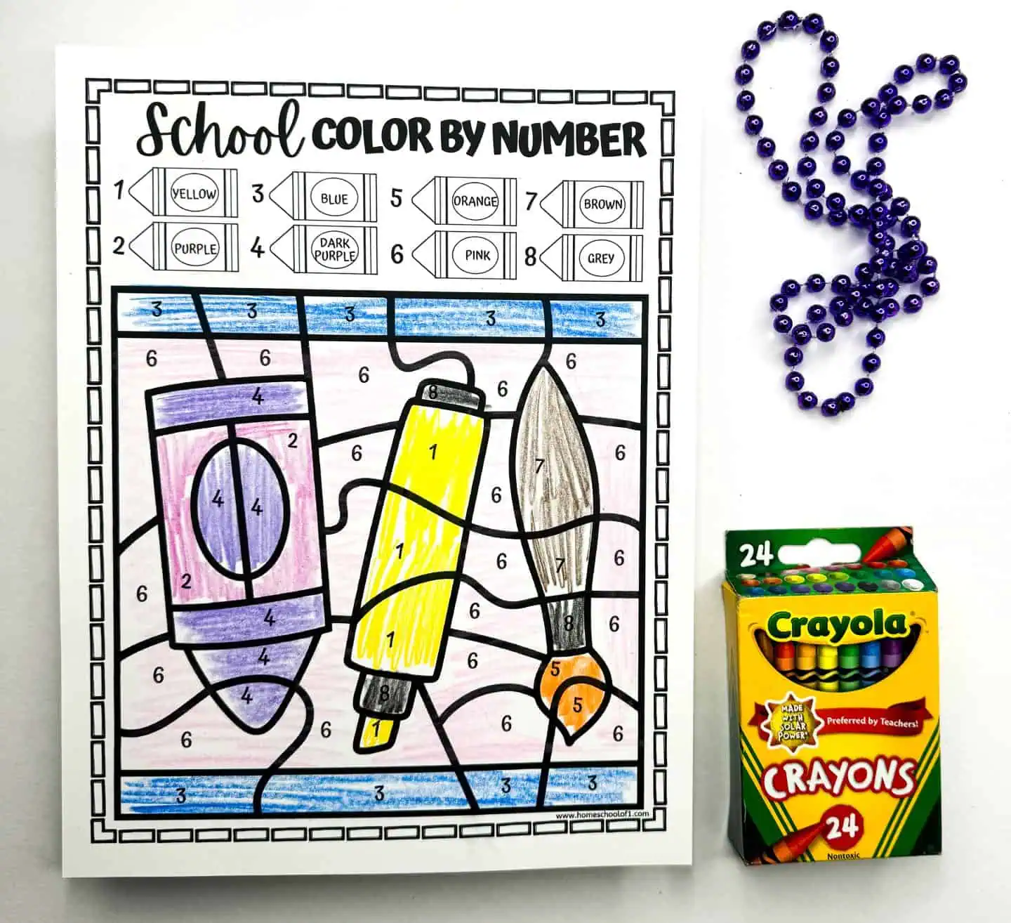 he worksheet displays various art supplies, including glue and scissors, filled in with vibrant hues as guided by the color key. A rabbit-shaped bead arrangement and a Crayola crayon pack suggest a creative art activity.