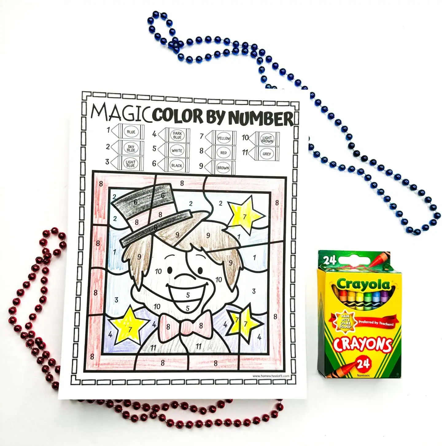 A color by number worksheet showing a cheery magician with a top hat and red bow tie, accompanied by a Crayola crayon box and red and blue beads.