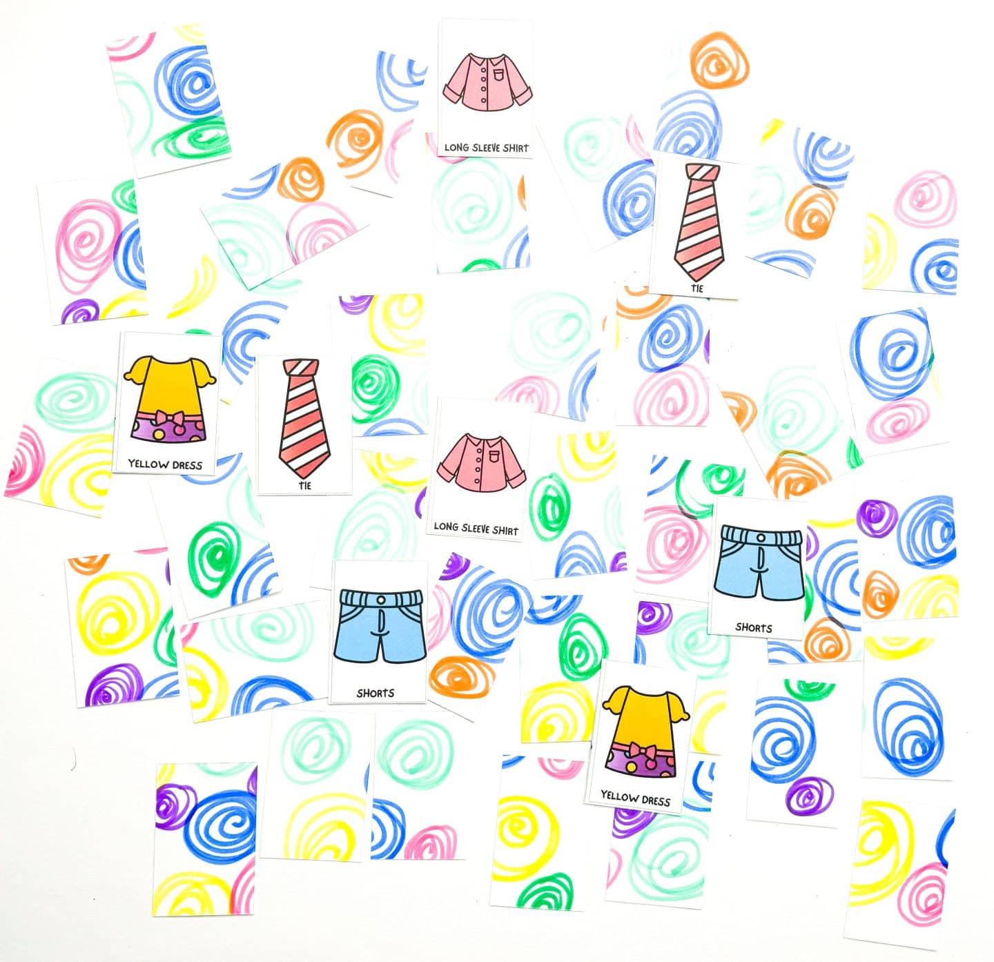 Partially matched sets from the 'Clothes Memory Game' with cards featuring a tie, yellow dress, shorts, and long sleeve shirt, alongside upside-down cards with colorful swirls.