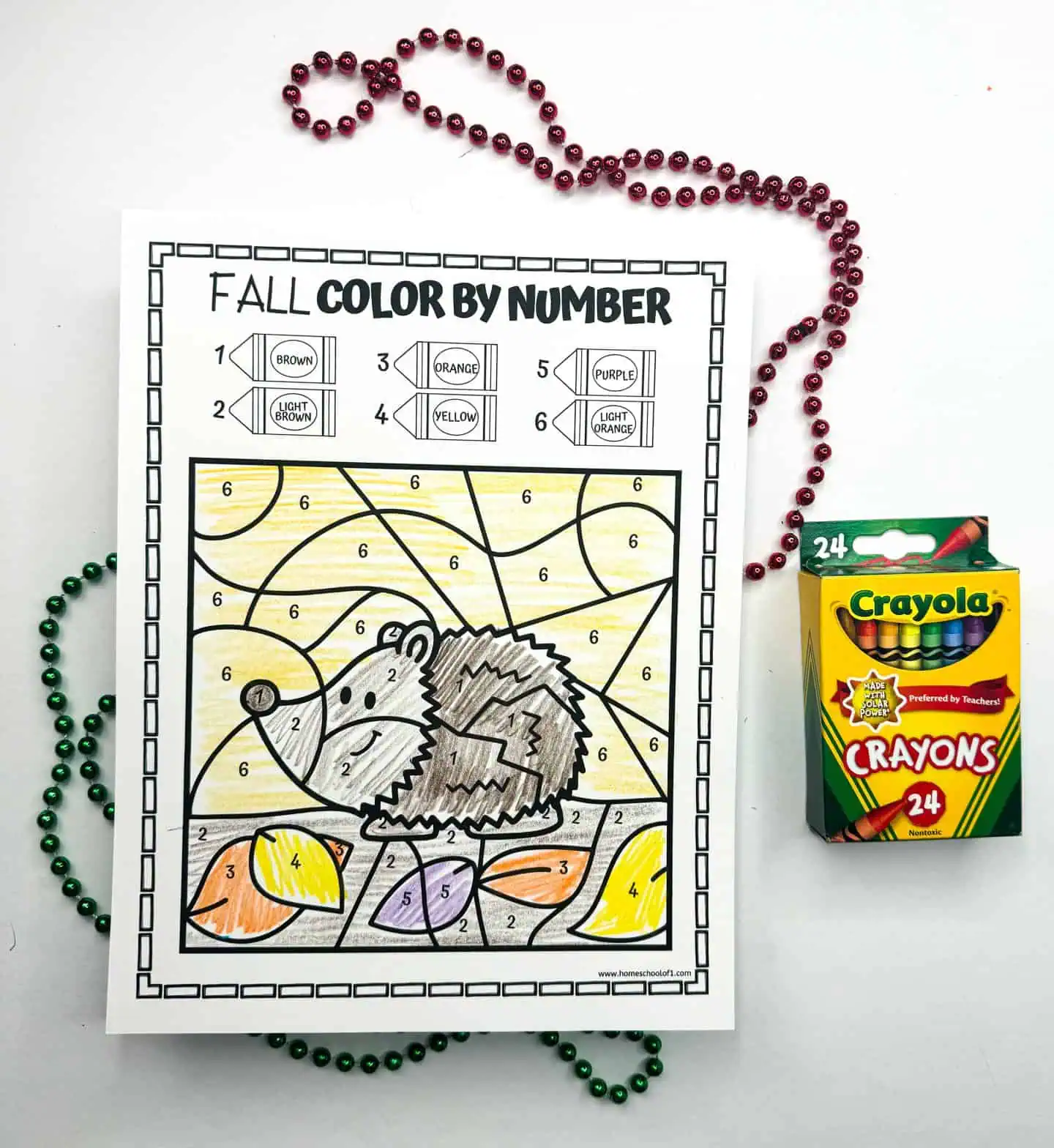 A 'Fall Color by Number' sheet featuring a cute hedgehog, paired with a box of Crayola crayons and colorful beads.