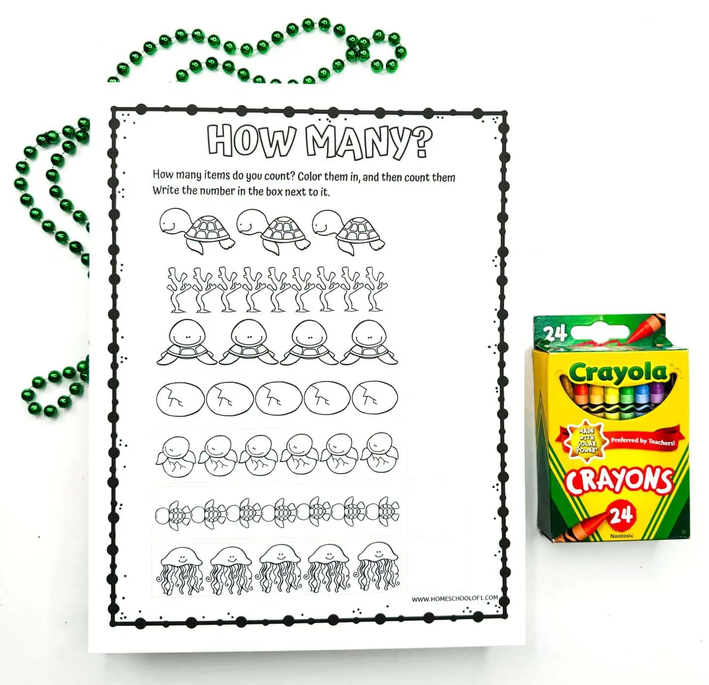 Worksheet titled 'HOW MANY?' with illustrations for children to count and color: turtles, happy suns, beach balls, smiling stars, octopuses, and jellyfish. A box of Crayola crayons and green decorative beads accompany the worksheet.