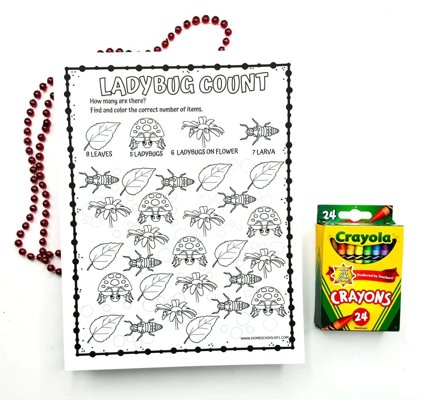 Children's counting worksheet with a 'Ladybug Count' theme, showing black and white drawings of leaves, ladybugs, ladybugs on flowers, and larvae to be colored, with a box of Crayola crayons and decorative red beads on the side.