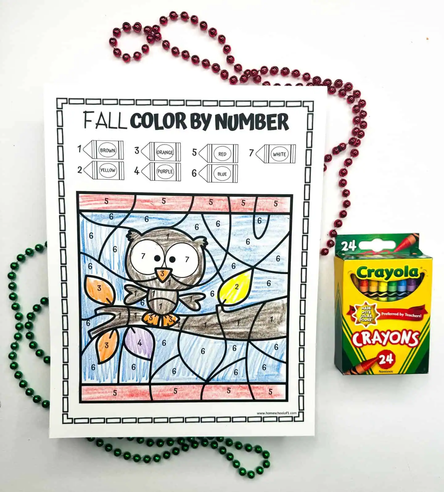 Printable worksheet of an owl perched on a branch for a color by number activity, with a Crayola crayons box and red beads.