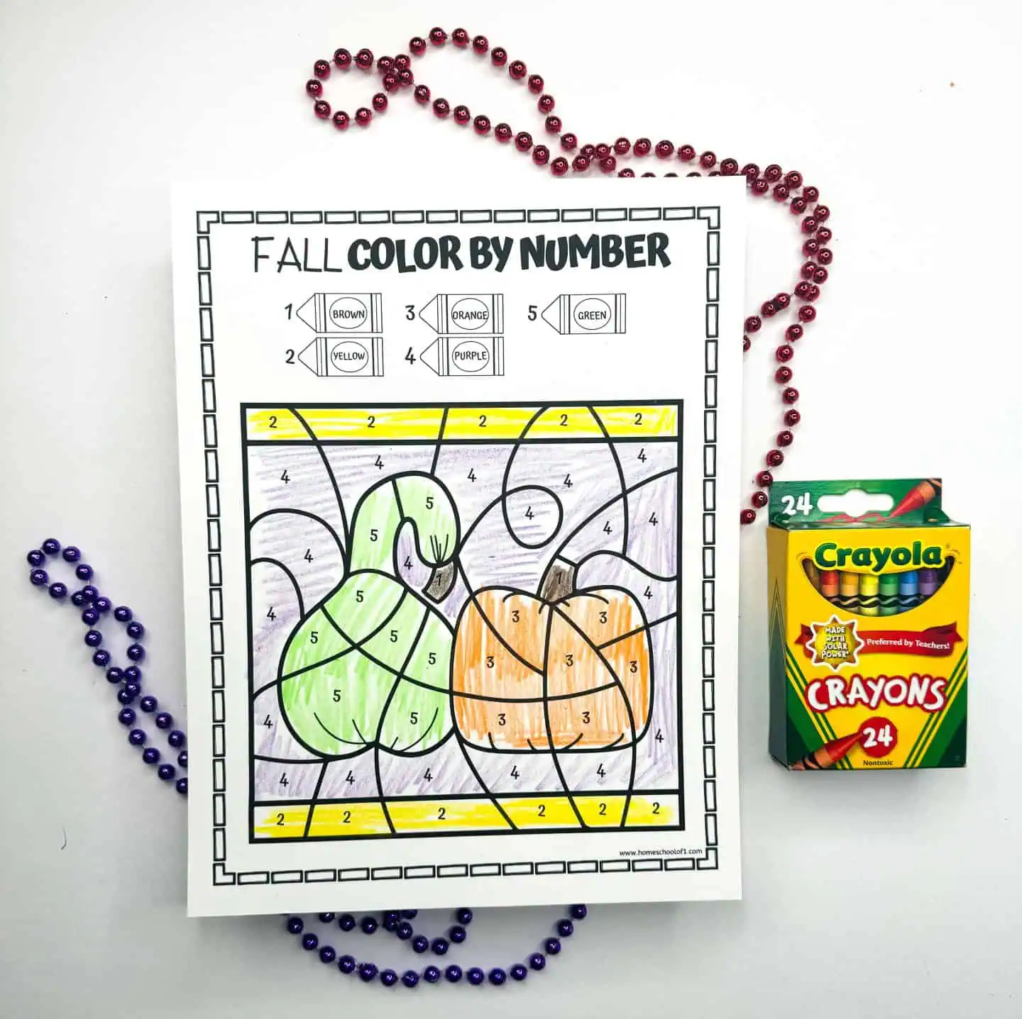 Color by number activity featuring plump pumpkins against a purple and red bead necklace background, with a Crayola crayons pack.