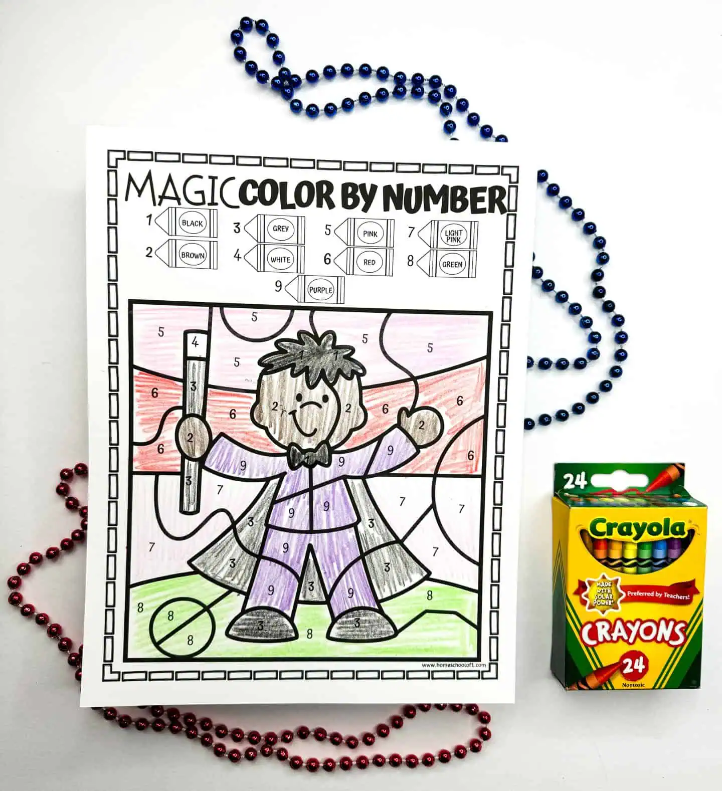 Color by number page with a joyful wizard holding a magic wand, with multicolored beads and a Crayola crayon pack alongside it.