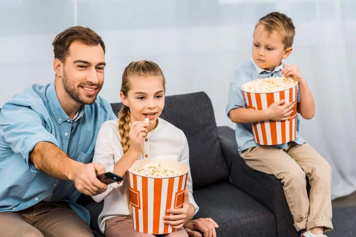 DADA AND HIS 2 CHILDREN WATCHING A MOVIE WHILE EATING POPCORN