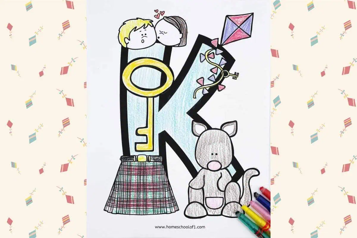 Coloring page featuring the letter 'K' with a large key, a kite, a kilt, and a kangaroo. The page includes a drawing of two children kissing above the letter 'K'. Colored crayons are placed next to the kangaroo illustration at the bottom right.